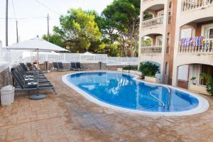 a swimming pool in front of a building at Apartamentos Quijote Park in Cala Ratjada