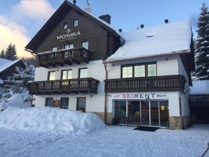 een gebouw met sneeuw op de grond ervoor bij Pension and Apartments MONIKA in Špindlerův Mlýn