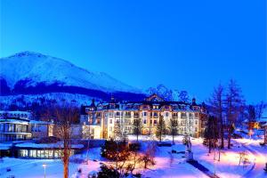 a large building in the snow in front of a mountain at Grand hotel Starý Smokovec in Starý Smokovec