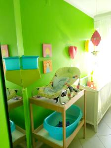 a childs room with green walls and a baby crib at Baby Boom - Duna Parque Group in Vila Nova de Milfontes