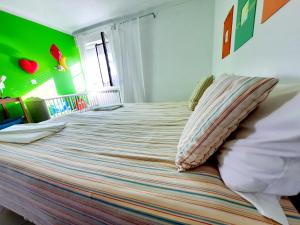 a large bed in a room with a green wall at Baby Boom - Duna Parque Group in Vila Nova de Milfontes