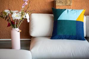 a white couch with a colorful pillow and a vase with flowers at Punta Marana in Santa Marinella