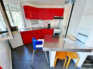a kitchen with red cabinets and a table and chairs at Baby Boom - Duna Parque Group in Vila Nova de Milfontes