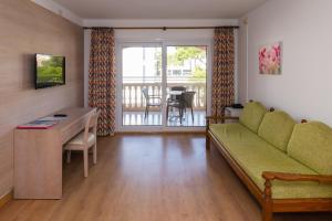 a living room with a green couch and a table at Apartamentos Quijote Park in Cala Ratjada