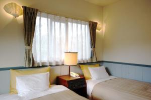 a hotel room with two beds and a window at Gardenvilla Shirahama in Shimoda