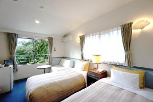 a hotel room with two beds and a window at Gardenvilla Shirahama in Shimoda