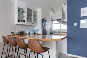 a kitchen with a counter with stools around it at Stunning Views, the Sea & Table Mountain! in Bloubergstrand