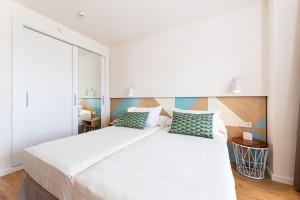 um quarto com uma grande cama branca com almofadas verdes em JS Portocolom Suites em Porto Colom