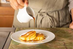a person pouring syrup onto a plate of food at Gardenvilla Shirahama in Shimoda