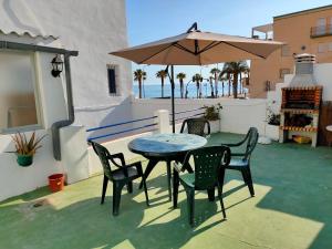 un patio con mesa, sillas y sombrilla en Tranquila casa frente al mar, en Adra