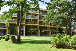 an apartment building with trees in front of it at Les Magnolias Hotel in Primorsko
