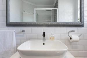 a white bathroom with a sink and a mirror at Stunning Views, the Sea & Table Mountain! in Bloubergstrand +16 photos