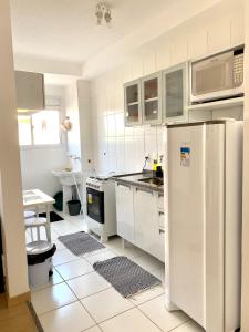a kitchen with white cabinets and a refrigerator at Apart. Manacá (Próximo a pista e rodoviária de Mogi Mirim). in Mogi-Mirim