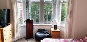 a room with a bed and a television and windows at Weaver's House B&B in Cardiff