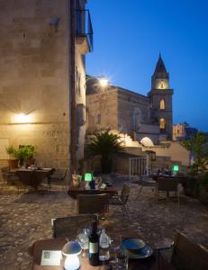 een openluchtrestaurant met tafels en een gebouw met een klokkentoren bij Residence San Pietro Barisano in Matera