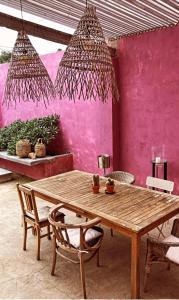 São Miguel House , Casa do Carvalhal في شنترين: طاولة وكراسي خشبية أمام جدار وردي