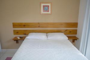um quarto com uma cama branca e uma cabeceira em madeira em Florianópolis Pousada Moçambeach em Florianópolis