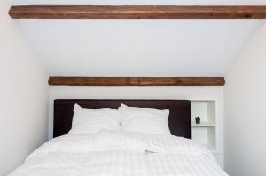 Bett mit weißer Bettwäsche und einem Kopfteil aus Holz in der Unterkunft Vakantiehuis De Bergplaats in Hapert