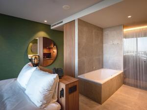 a bathroom with a large tub and a large mirror at Van der Valk Hotel Amsterdam Zuidas -Rai in Amsterdam