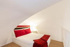 un letto bianco con cuscini rossi in una stanza bianca di Charming Studio near Piazza Castello by Wonderful Italy a Torino