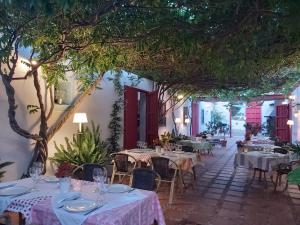 ein Restaurant mit weißen Tischen, Stühlen und Bäumen in der Unterkunft Hotel Cortijo del Arte - Caminito del Rey in Pizarra