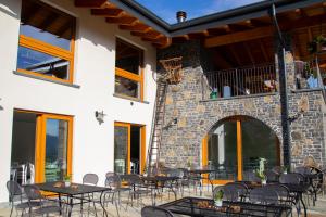 a patio with tables and chairs and a stone wall at Sole Agriturismo in Locatello