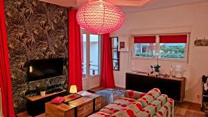 - un salon avec des rideaux rouges et un lustre dans l'établissement Villa Kady - Chalet de charme du 19ième siécle, à Le Touquet-Paris-Plage