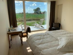 een slaapkamer met een bed, een bureau en een raam bij In 't Groen in Watou
