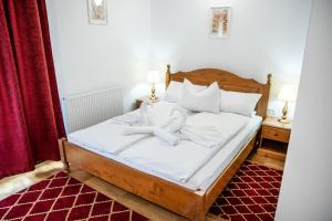 1 dormitorio con 1 cama con sábanas y almohadas blancas en VILLA GHERMAN, en Sălciua de Jos