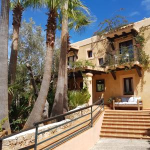 une maison avec des palmiers devant elle dans l'établissement Casa Naya Rural, à Sant Llorenç de Balafia