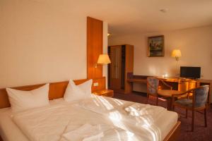 ein Hotelzimmer mit einem weißen Bett und einem Schreibtisch in der Unterkunft Hotel Kutzbach in Reuterstadt Stavenhagen