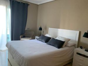 ein Schlafzimmer mit einem großen weißen Bett mit zwei blauen Kissen in der Unterkunft Apartamento Balcón del Puerto in Tazacorte + 37 Fotos