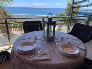 einen Tisch mit Tellern und Utensilien auf einem Balkon mit Strandblick in der Unterkunft Apartamento Balcón del Puerto in Tazacorte