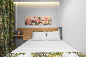 a bedroom with a bed with white sheets and pink flamingos at Elle in Thessaloniki