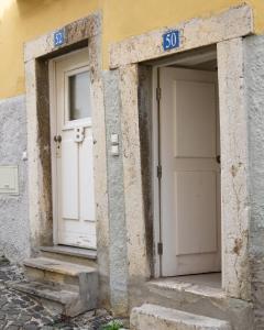 two white doors on the side of a building at Alfama Yellow House in Lisbon