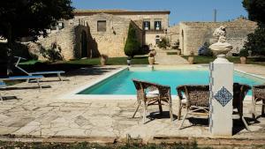Una piscina con sillas y una mesa y un edificio. en Villa Castiglione 1863 - The real Sicilian holiday, en Ragusa