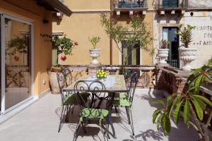 einen Tisch und Stühle auf einer Terrasse mit Pflanzen in der Unterkunft Le Terrazze del Teatro Greco in Taormina