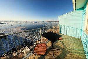 a balcony with two chairs and a table and the ocean at Hotel Icefiord in Ilulissat