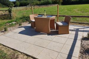 a patio with a table and two chairs and a bottle of wine at The Piggery - Corfe Mullen in Corfe Mullen