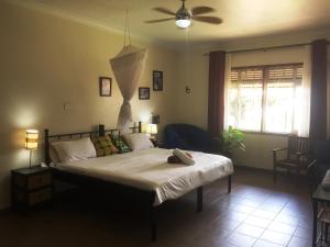 een slaapkamer met een bed en een plafondventilator bij Carpe Diem Guesthouse in Entebbe