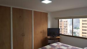 - une chambre avec un lit, une télévision et une fenêtre dans l'établissement Apartosuites cerca del Boulevar de Sabana Grande y la Av. Solano, à Caracas