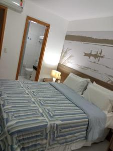 een slaapkamer met een groot bed en een schilderij aan de muur bij ILOA Residence Apt Completo in Barra de São Miguel