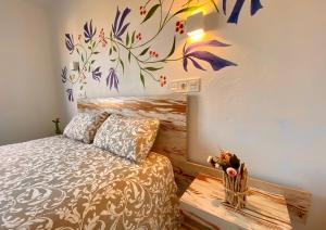 - une chambre avec un lit orné d'une fresque murale représentant des fleurs dans l'établissement Las Casetas de Mateu, à Torres del Obispo