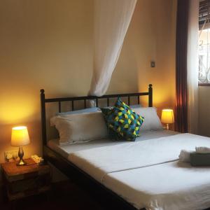 Schlafzimmer mit einem Bett mit weißer Bettwäsche und Kissen in der Unterkunft Carpe Diem Guesthouse in Entebbe