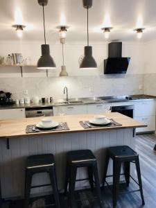 a kitchen with a counter with three stools and a sink at Apartments At The Sentrum in Kristiansund