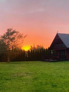 una puesta de sol en un campo junto a una cabaña en Domki całoroczne nad zalewem, en Świnoujście