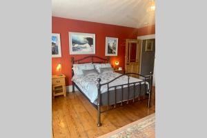 a bedroom with a bed and a red wall at Stunning 18th Century 5 Bed House Old-Town Hastings in Hastings