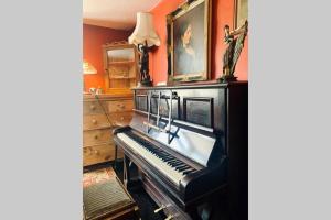 a piano in a room with orange walls at Stunning 18th Century 5 Bed House Old-Town Hastings in Hastings