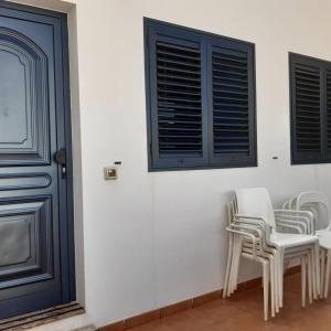Habitación con sillas blancas y puerta azul en Casa Carmen Dolores, en Caleta de Sebo