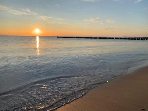 a beach with a pier in the water at sunset at Ferienwohnung PuraVida Ostsee 5A in Kühlungsborn +2 photos